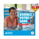 Donneur souriant pendant un don de sang dans une salle lumineuse.